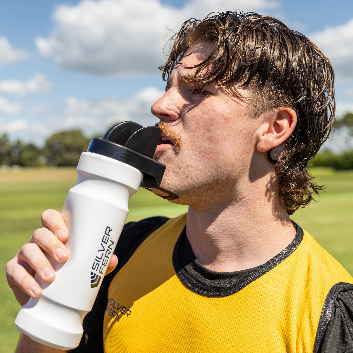 Hygiene drink bottle, lifestyle shot, rugby player squeezing the bottle and drinking water out of the hygiene chin rest cap